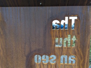 Rusted iron sign with the message Tha Thu An Seo cut into it viewed from the back